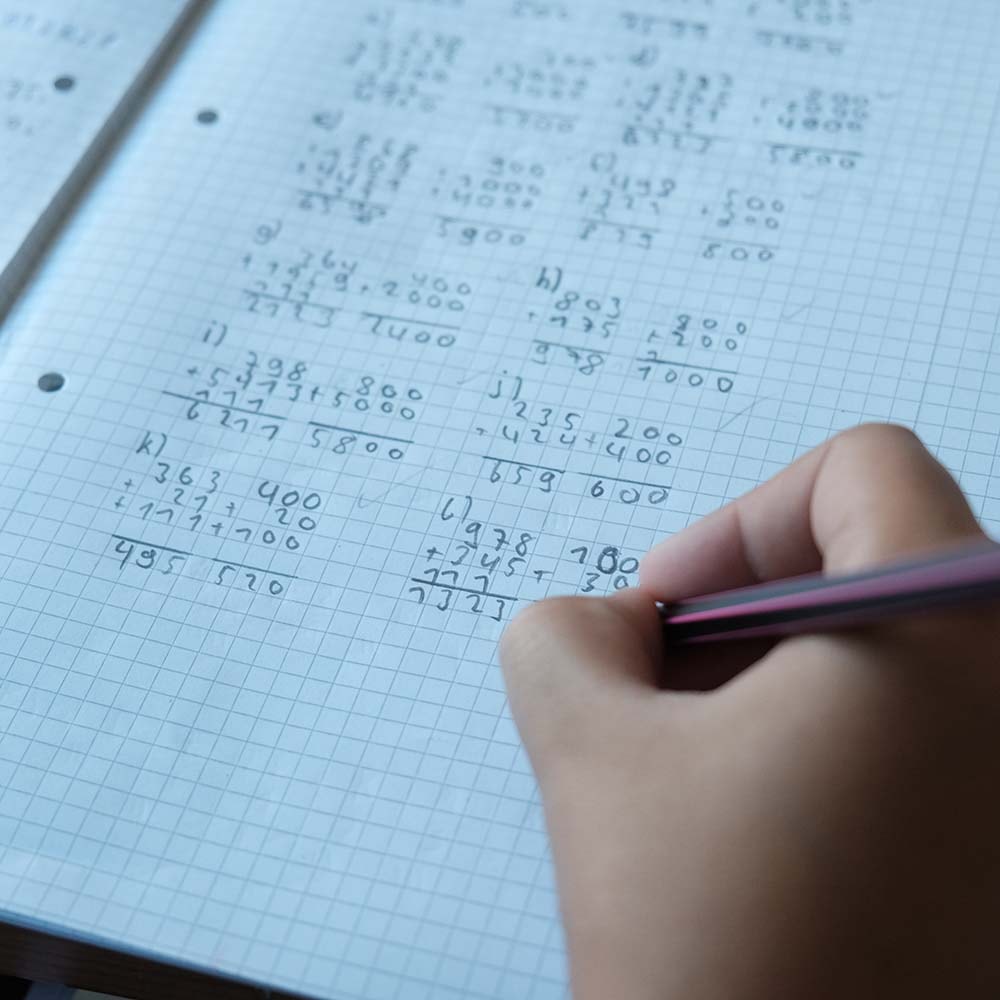 Ein Kind schreibt in seinem Matheheft